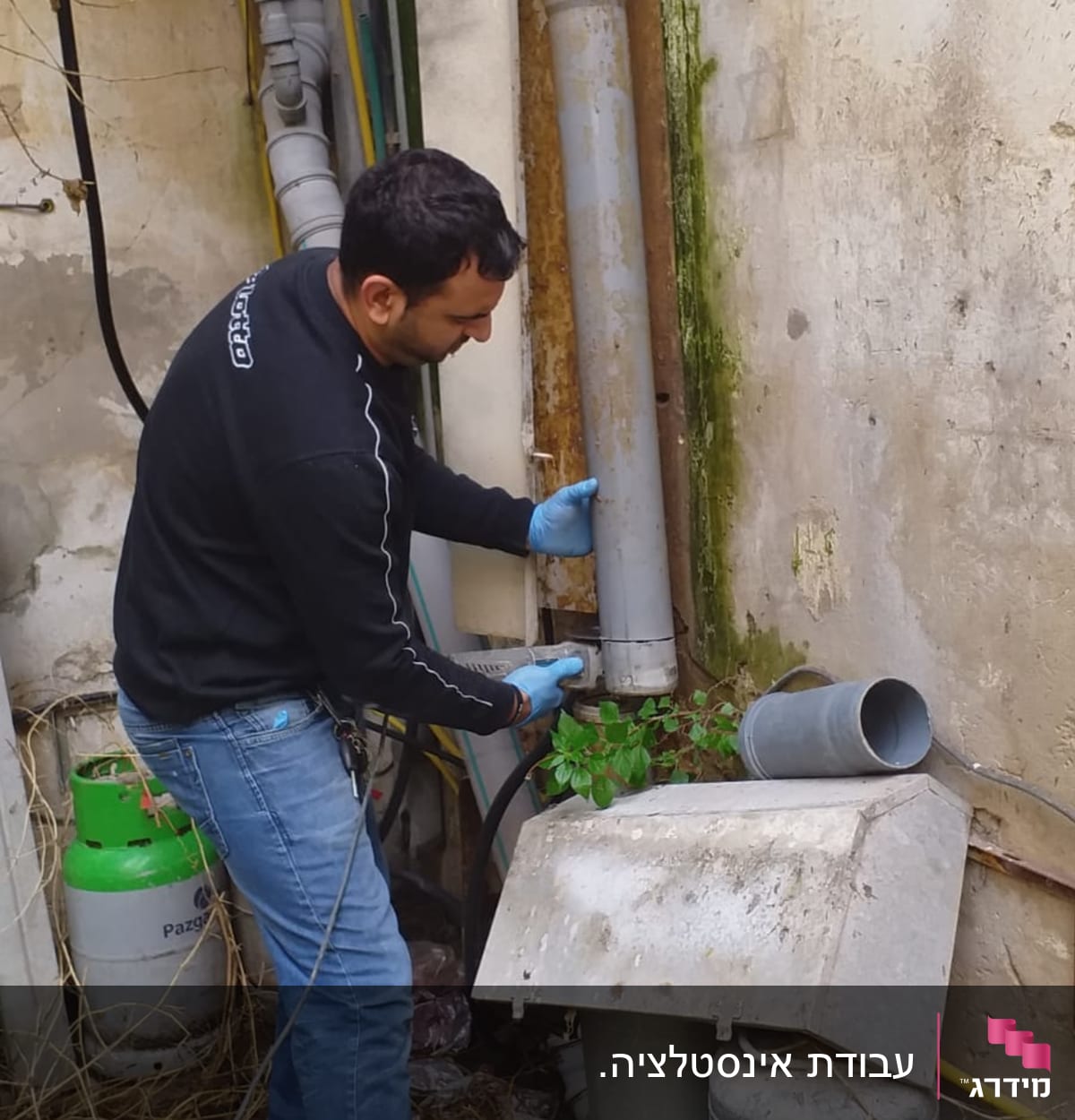 אדם עם כפפות מתקין צינור חיצוני ליד קיר